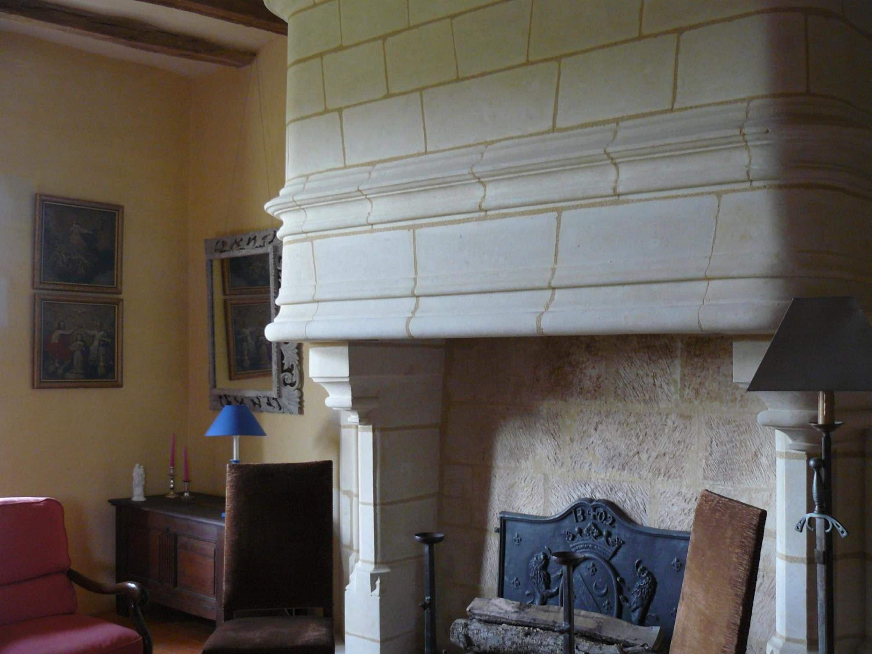 A room with a fireplace, a red chair, a blue lamp, and framed artwork on the wall.