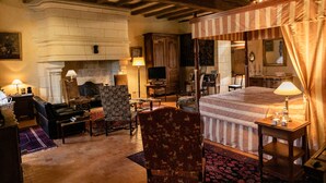Une chambre traditionnelle dotée d’une cheminée, d’un lit à baldaquin et d’un coin salon avec un canapé et des fauteuils.
