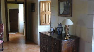 A hallway with a wooden door, a cabinet with drawers, a lamp, and a framed picture on the wall.