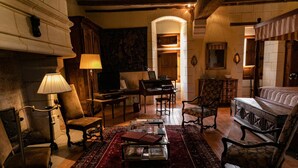 Une pièce de style traditionnel, dotée d’une cheminée, d’un piano, d’un lit à baldaquin et d’un tapis rouge.