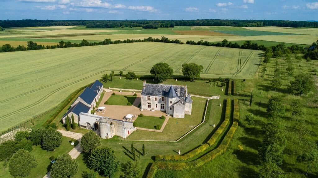 Un'ampia tenuta con un edificio principale, un annesso più piccolo e vasti campi.