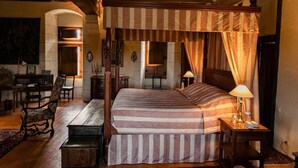Une chambre de style traditionnel, dotée d’un lit à baldaquin, d’un bureau avec une chaise et d’une petite table avec une lampe.