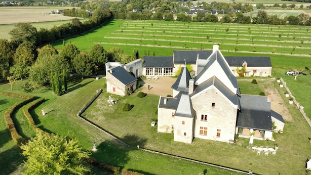 Un vaste domaine comprenant plusieurs bâtiments, dont une maison principale dotée d’un toit en pente et plusieurs dépendances plus petites.