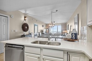 A modern kitchen with a large island, stainless steel appliances, and a view to the outside.