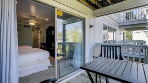 A room with a bed, a table, and a balcony with a railing. - Award-Winning Resort Amenities | Lagoon Villa 3 (Isle of Palms)