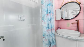 Une salle de bain avec une douche, un lavabo et un miroir.
