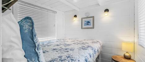 A bedroom with a bed, a bedside lamp, a wall clock, and a framed picture.
