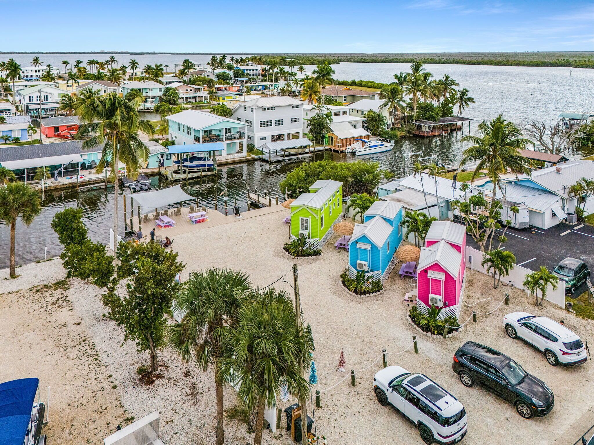 Uma área residencial costeira com casas coloridas, um porto de iates e uma praia arenosa.