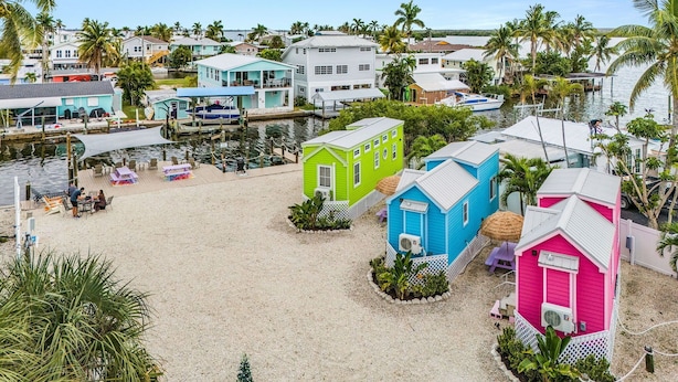 A beachside area with colorful beach houses, a dock, and a sandy beach. - Matlacha Tiny Village (Matlacha)