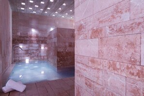 A spa room with a marble floor and walls, a shower area, and a towel on the floor. - Spa la Romana (La Romana)