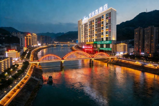 A hotel with a modern design, located beside a river with a bridge.