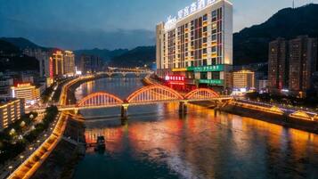 A hotel with a modern design, located beside a river with a bridge.