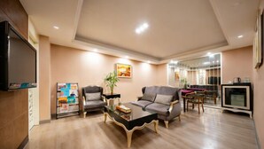 A spacious living room with a large flat-screen TV, two sofas, a coffee table, and a dining area with a glass partition. - Archos Boutique Hotel (Ankang)