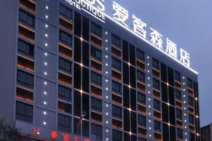 Un edificio de hotel con varios pisos, ventanas iluminadas y un letrero que indica que es un hotel.