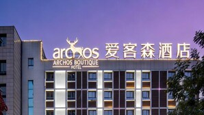 Ένα ξενοδοχείο με το όνομα «Archos Boutique Hotel», με μια μοντέρνα πρόσοψη και φωτεινή επιγραφή.
