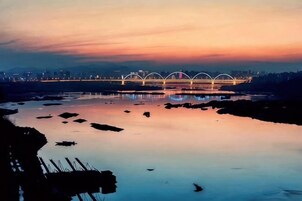 Un puente con múltiples arcos sobre un río tranquilo al atardecer.