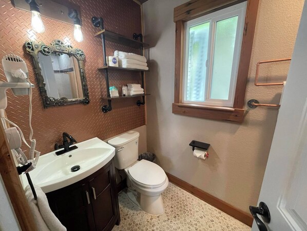 A bathroom with a sink, toilet, and a window.