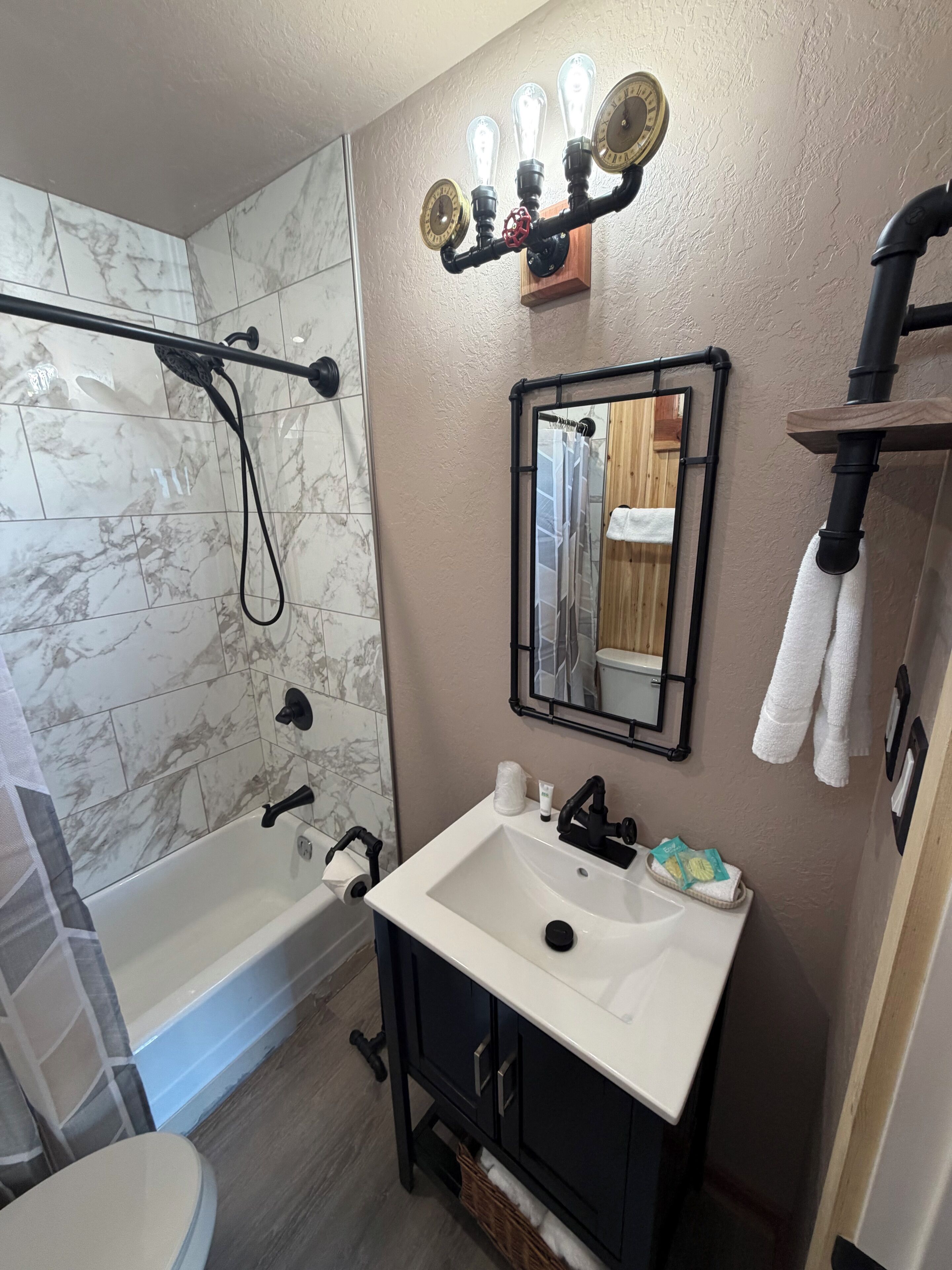 A bathroom with a shower, a sink, a mirror, and a towel rack.