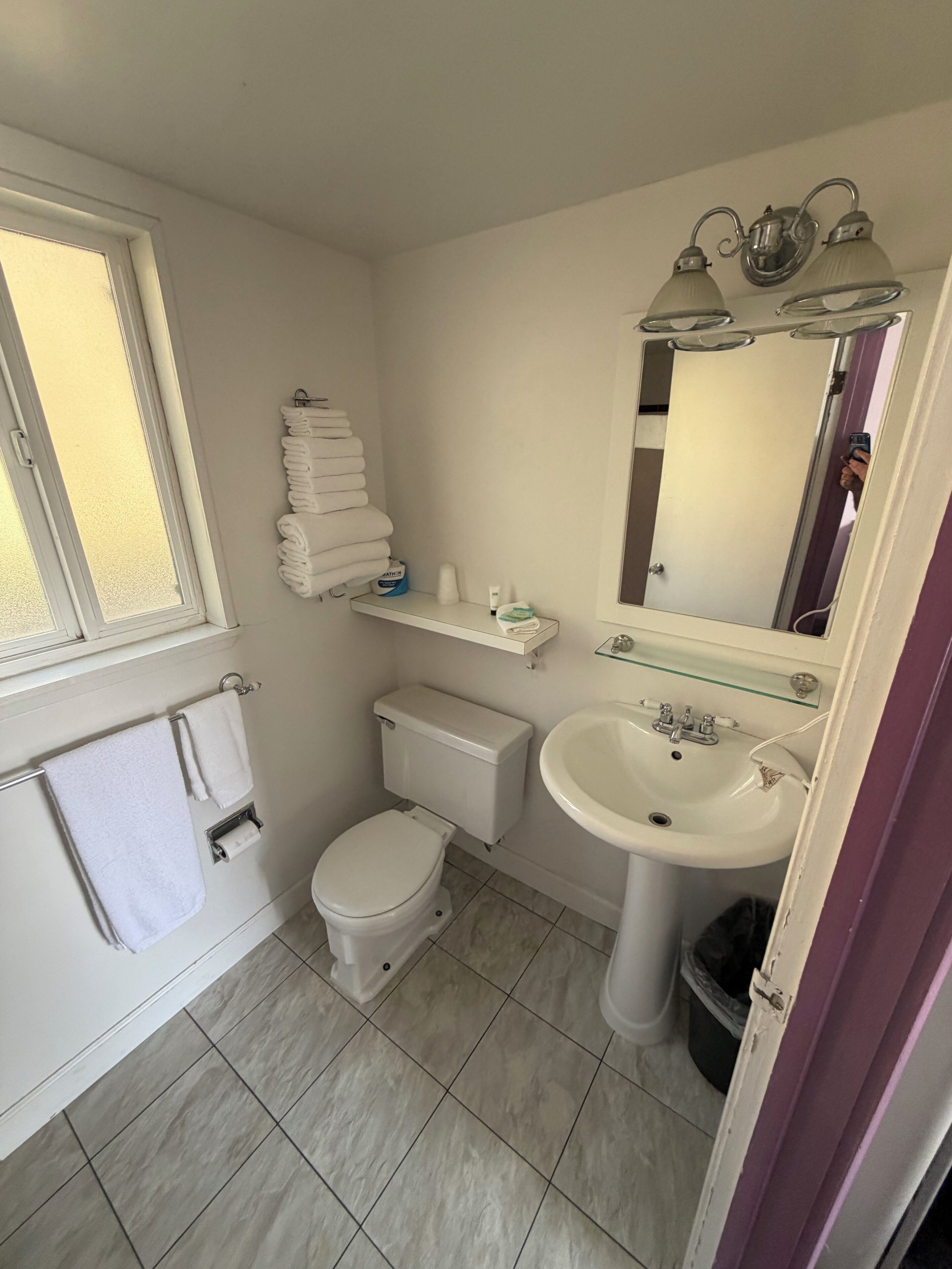 A compact bathroom with a toilet, sink, and a mirror above it.