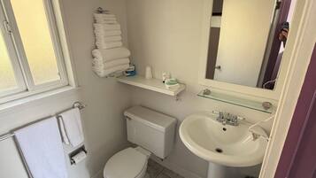 A compact bathroom with a toilet, sink, and a mirror above it.