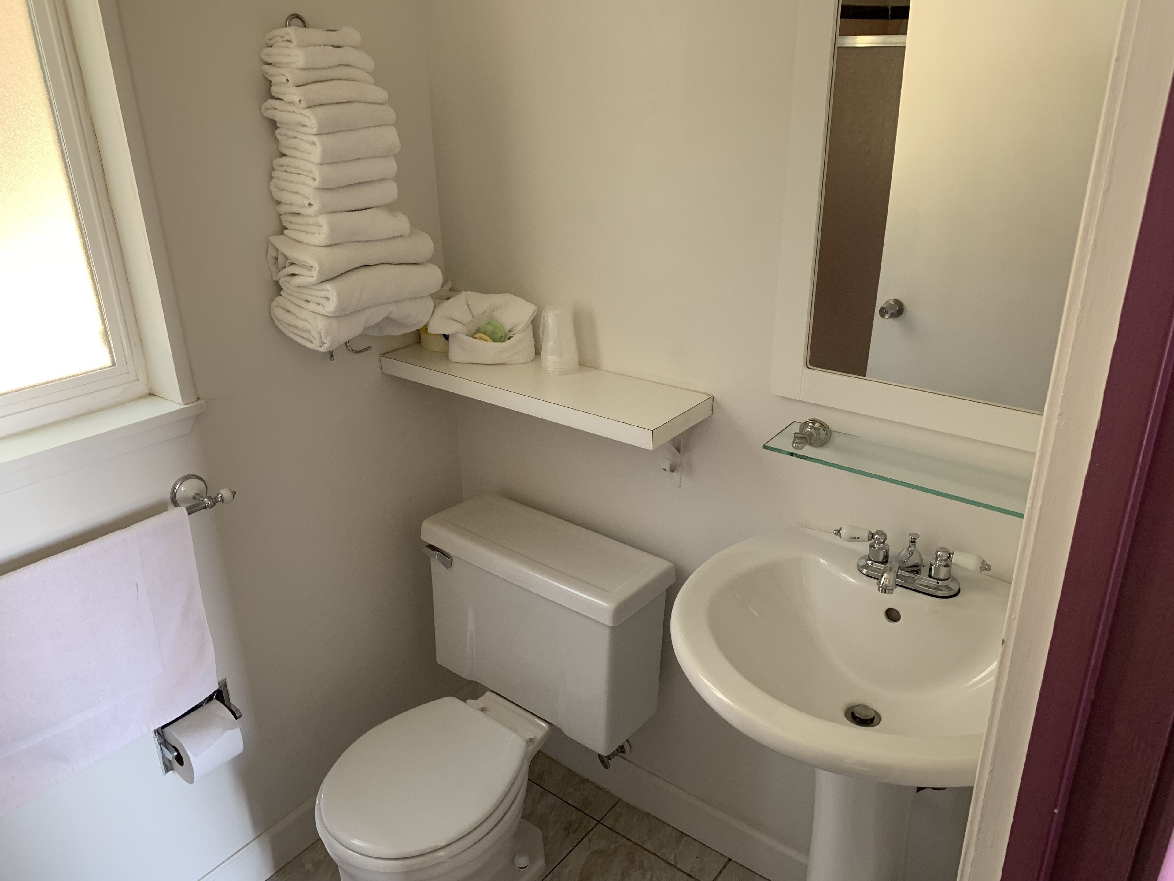A small, clean bathroom with a toilet, sink, and towel rack.