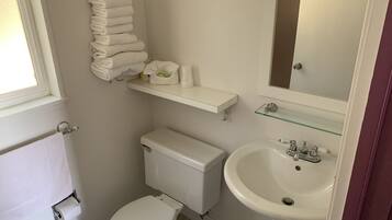 A small, clean bathroom with a toilet, sink, and towel rack.