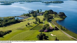 An aerial view of the 18th hole on the Killeen Course at Killarey Golf and Fishing Club, featuring a well-maintained golf course, water bodies, and surrounding greenery. - Tatler Jack (Killarney)