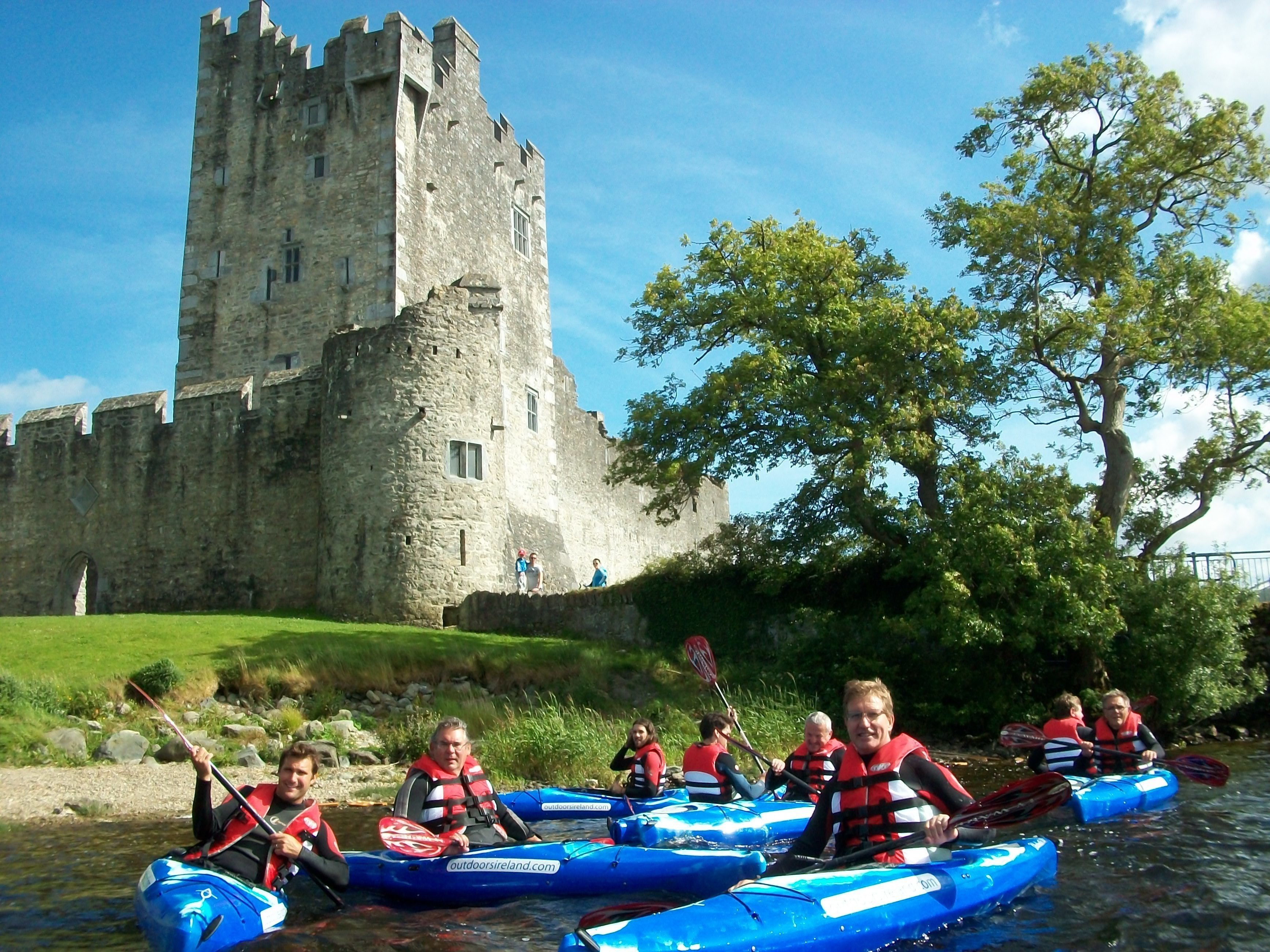 A group of people kayaking in front of a historic castle.