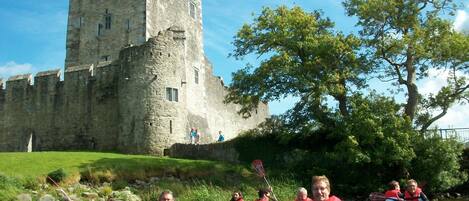 A group of people kayaking in front of a historic castle.
