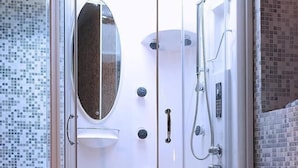 Une salle de bain moderne avec une douche à parois de verre, une chaise noire et une baignoire.