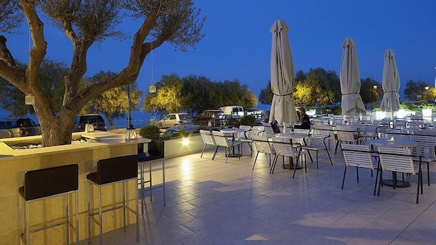 Un espace extérieur aménagé avec des tables, des chaises, des parasols et un arbre.