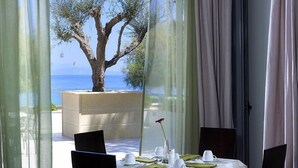 Une table dressée pour le dîner, avec vue sur la mer et un arbre.