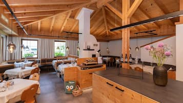 Ein Restaurant mit Holzeinrichtung, mehreren Tischen und einer zentralen Insellaterung mit Blumen.