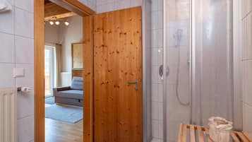 Eine Holztür, die zu einem Badezimmer mit Dusche und Sitzbank führt.