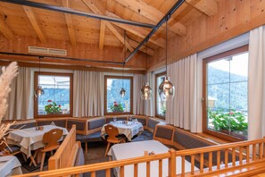 A restaurant with wooden interior, large windows, and a view of the mountains.