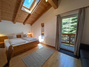 A bedroom with a wooden bed, a large window, and a view of the outdoors.