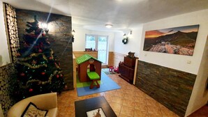 A living room with a Christmas tree, a playhouse, a fireplace, and a painting on the wall. - Hostel & Apartments u Florka 2 (Zakopane)