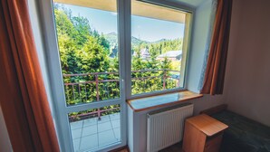 A room with a large window overlooking a balcony with a view of trees and houses. - Hostel & Apartments u Florka 2 (Zakopane)