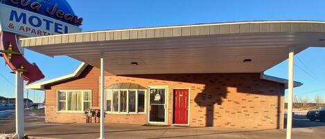A motel with a red door and a covered parking area.