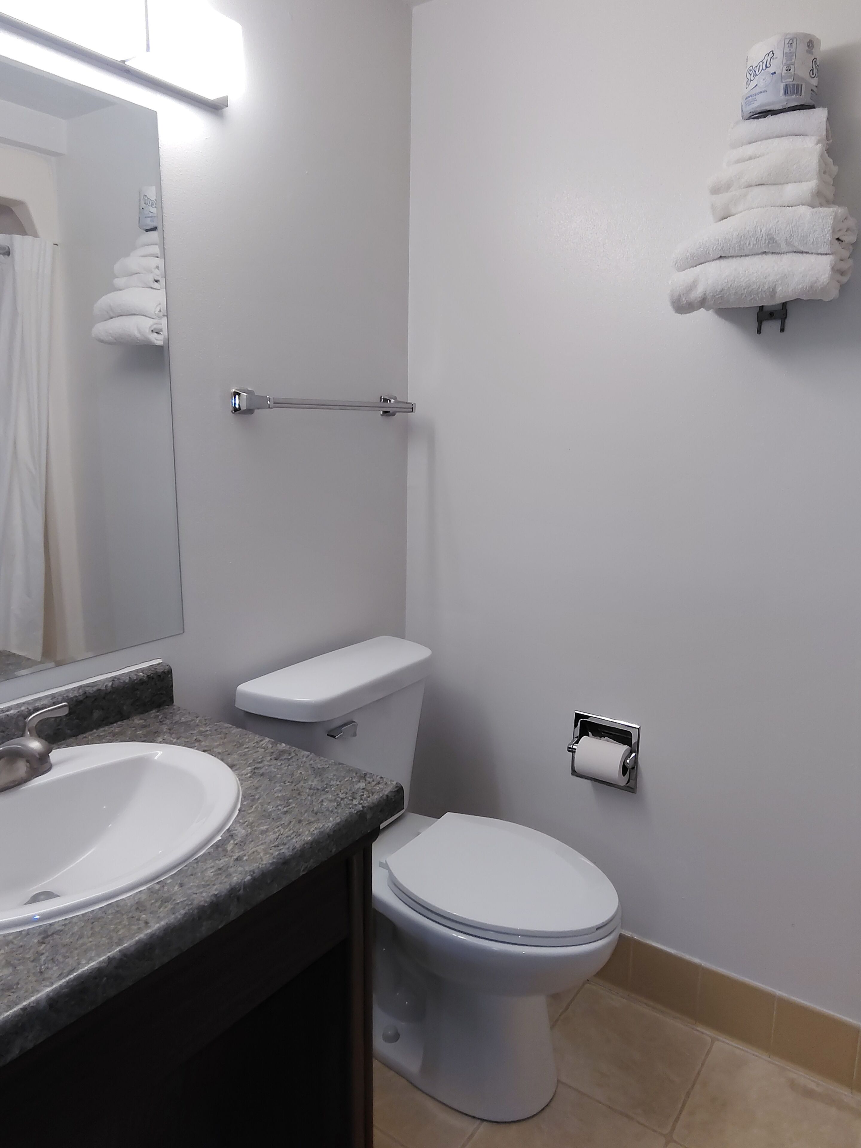 Une salle de bain équipée d’un lavabo, de toilettes, d’un porte-serviettes et d’un miroir.