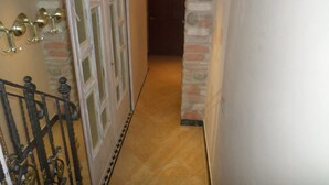 Un pasillo con pared de piedra, suelo de madera y una puerta al final.