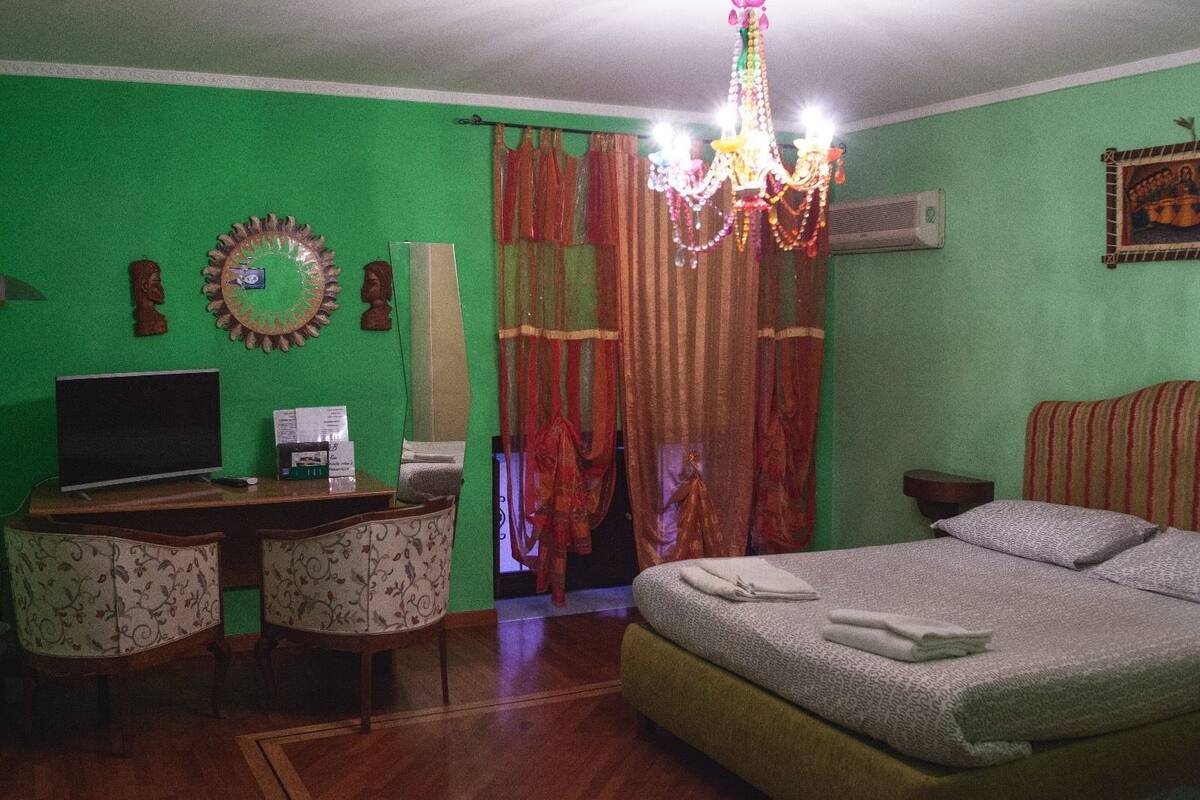 Un dormitorio con cama, un escritorio con televisor, una silla y una araña.