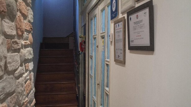 Una escalera que lleva a una habitación con una pared de piedra a un lado y una puerta con detalles azules y un cartel en la pared.