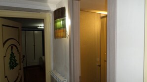 Un pasillo con un radiador, una puerta y un accesorio de luz en la pared.