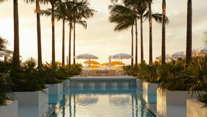 Una piscina con vistas a palmeras y sombrillas.