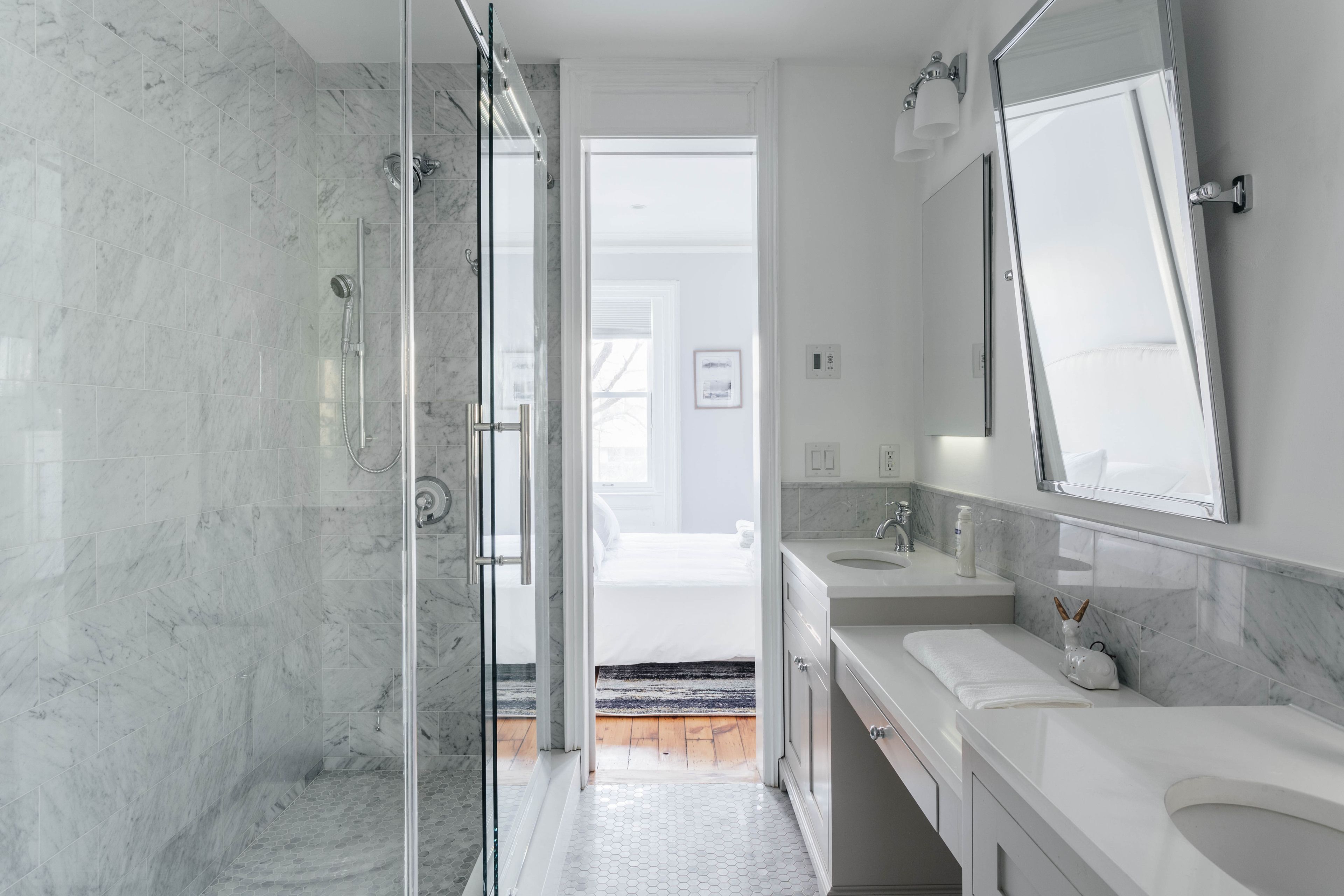 A modern bathroom with a glass shower enclosure, two sinks, and a large mirror.