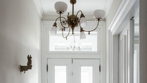 Un couloir doté d’un plancher en bois, de portes blanches et d’un lustre.