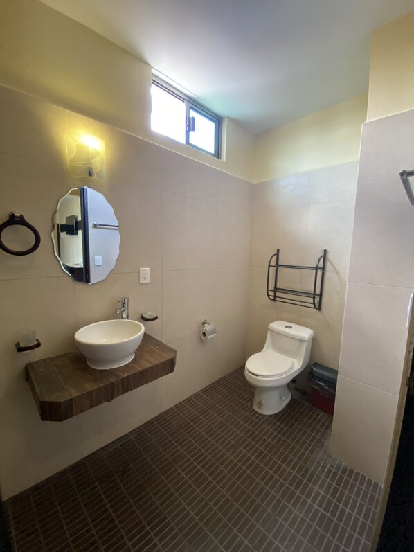 Une salle de bain avec un lavabo, un miroir, des toilettes et une fenêtre.