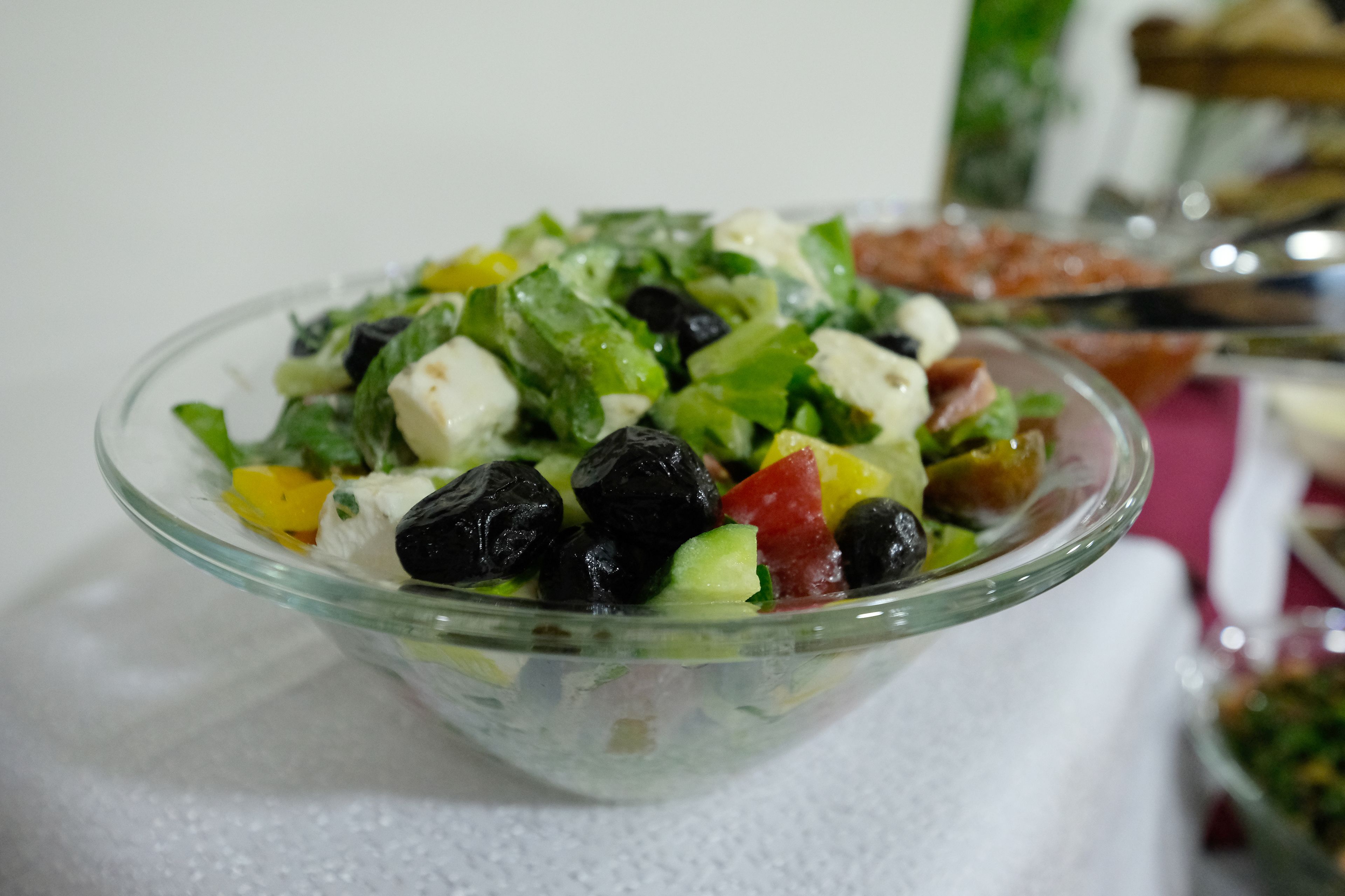 Een glazen schaal met een salade en verschillende ingrediënten.