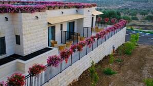 A modern building with a stone facade, outdoor seating, and flower boxes along the balcony. - Tantur Hills Hotel - Jerusalem (Jerusalem)